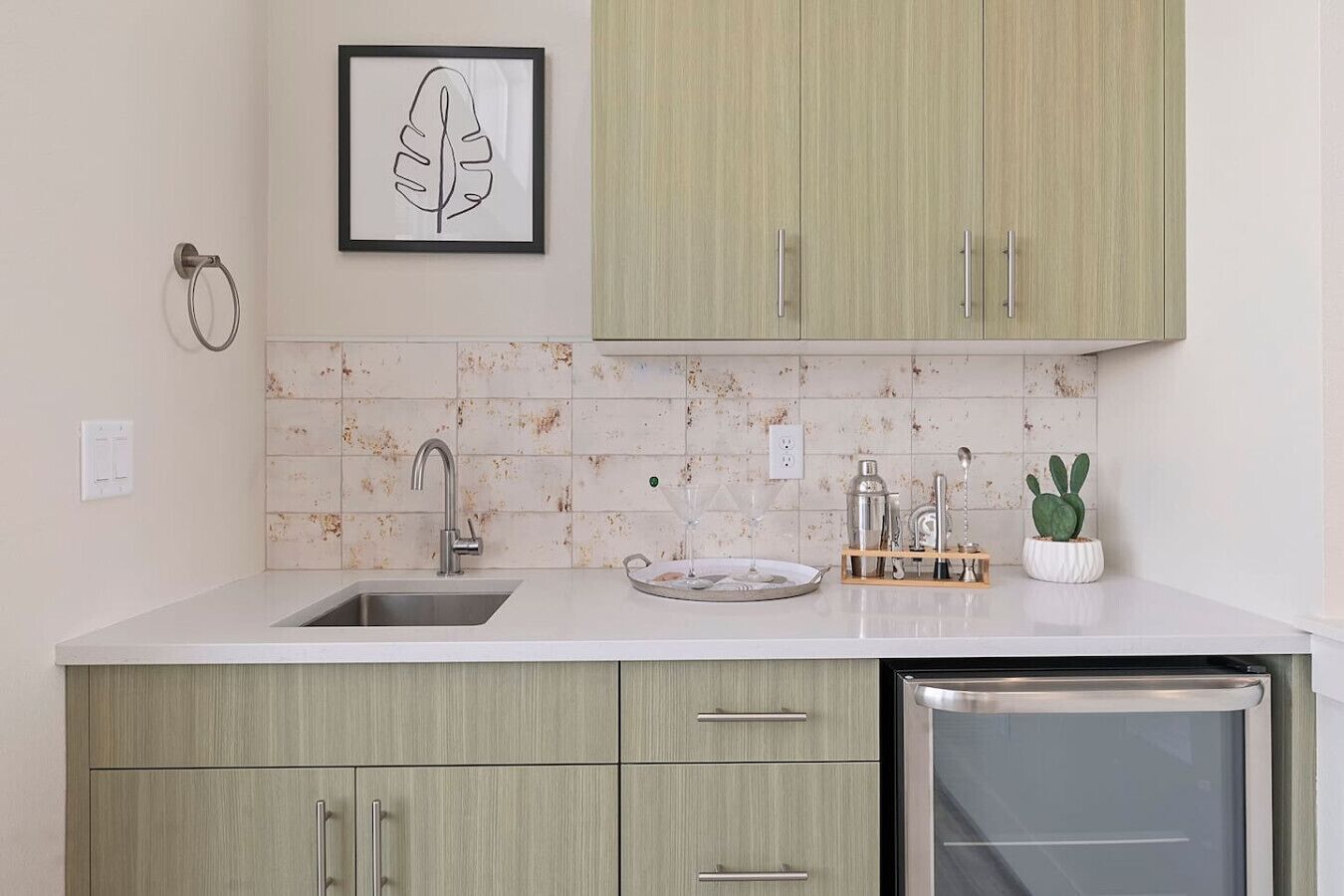Una cocina con un lavaplatos, un lavamanos y una encimera con una planta y utensilios.