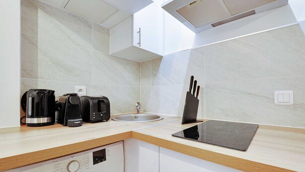 Une cuisine moderne équipée d’un lave-vaisselle encastré, d’un évier et d’une plaque de cuisson à induction noire.