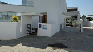 A modern building with a white facade, a visible entrance, and a small sign indicating room number 13.