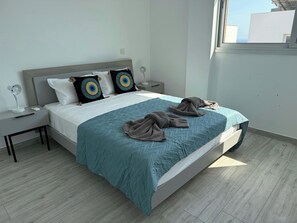 Une chambre moderne avec un lit, deux tables de chevet, une commode et une fenêtre.