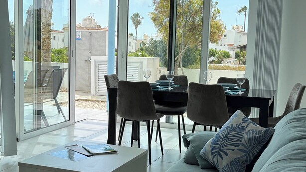 Ein modernes Wohnzimmer mit einer Couch, einem Couchtisch und einem Essbereich mit Stühlen und einem Tisch.
