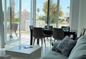 A modern living room with a sofa, a coffee table, and a dining area with chairs and a table.