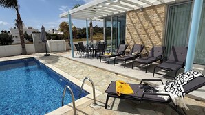 Ein Swimmingpool mit Liegestühlen und einer überdachten Terrassenfläche.