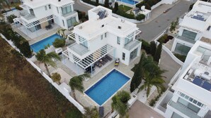 Ein modernes, mehrstöckiges Wohngebäude mit Pool auf dem Dach, Solaranlage und überdachter Außenbereich zum Sitzen.