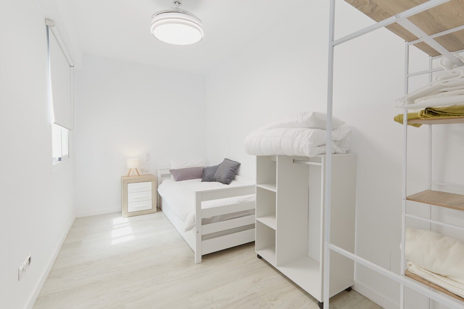 Minimalistinen makuuhuone, jossa on sänky, yöpöytä ja vaatekaappi.