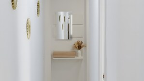 A narrow hallway with white walls, a wooden floor, and a white door at the end.