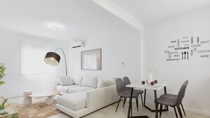 A modern living room with a white sofa, a dining table with chairs, a pendant light, and a wall with food-related words.