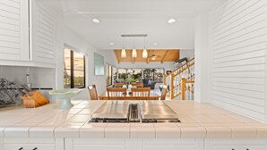 Een moderne keuken met een centraal eiland, houten balken in het plafond, en een eethoek met uitzicht.
