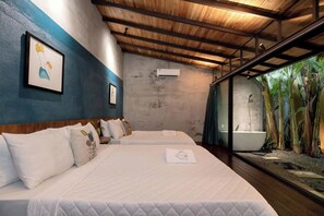 Ein Schlafzimmer mit zwei Betten, einem großen Fenster mit Blick auf Pflanzen und einer Decke mit freiliegenden Balken.