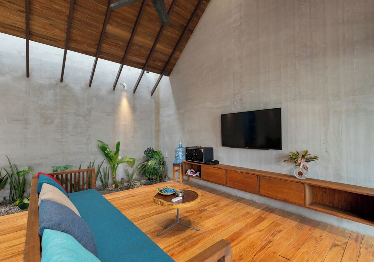 Una sala de estar moderna con piso de madera, un sofá azul, una mesa de centro y un televisor montado en la pared.