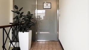 A modern hotel entrance with a glass door, a potted plant, and a sign indicating it's a luxury home. - Esposizione Luxury Rome (Rome)