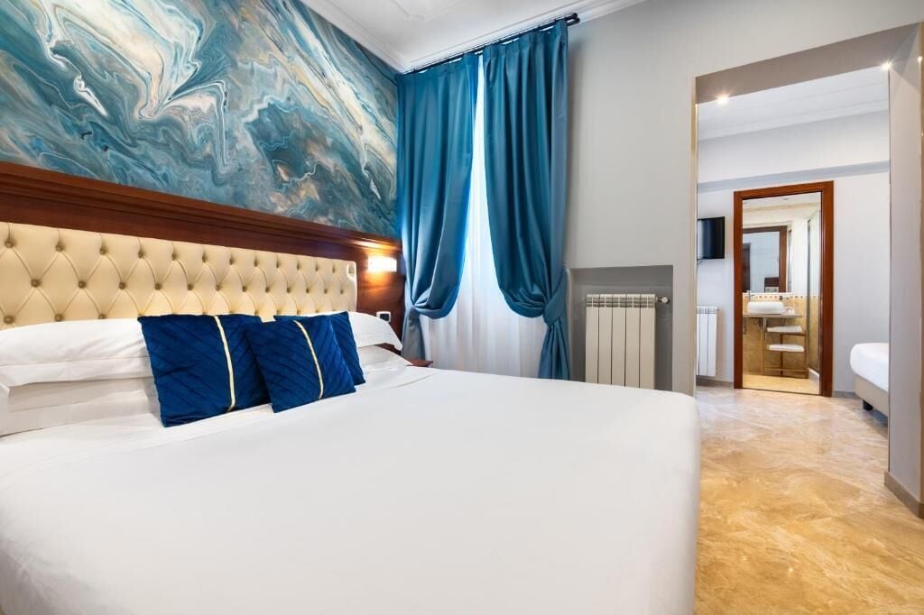 A hotel room with a large bed, a marble floor, a marble wall, and a view of the bathroom.