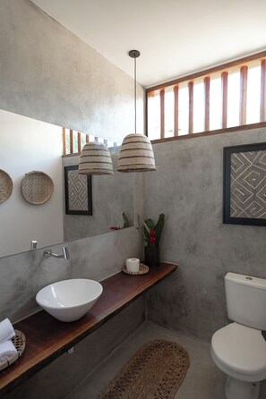 A modern bathroom with a large mirror, a white sink, a wooden vanity, a toilet, and a shower area. - Casa Canoa Paraty (Paraty)