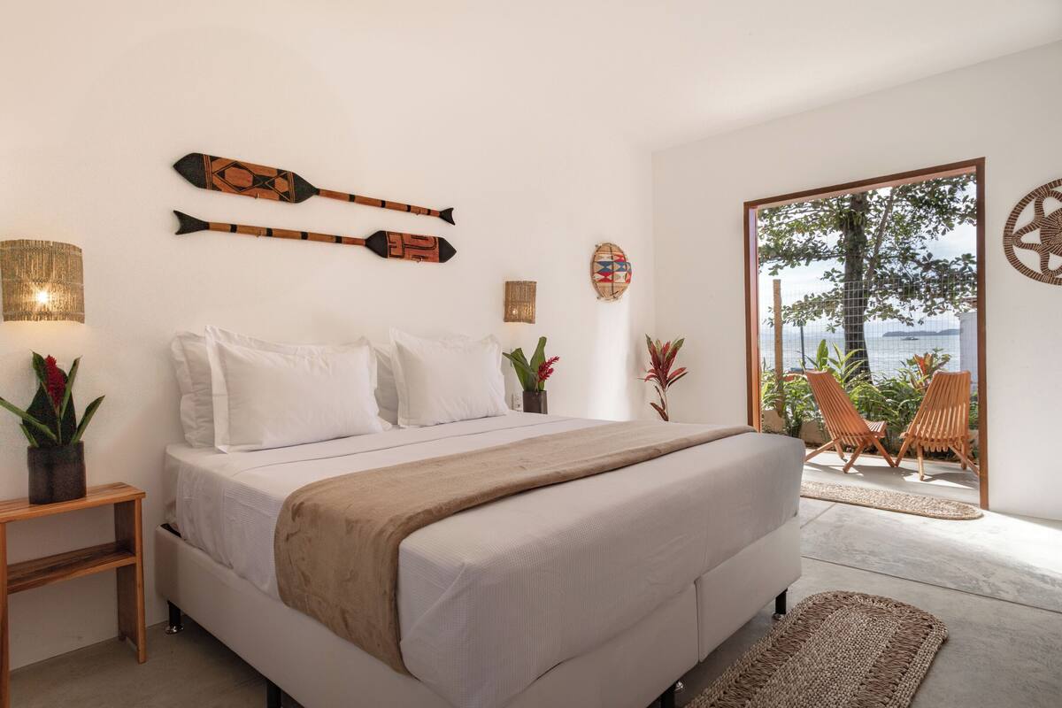 A bedroom with a bed, bedside tables, and a view of the outside.