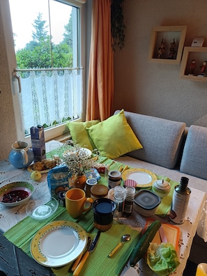A dining table set with various dishes, utensils, and a window with curtains.