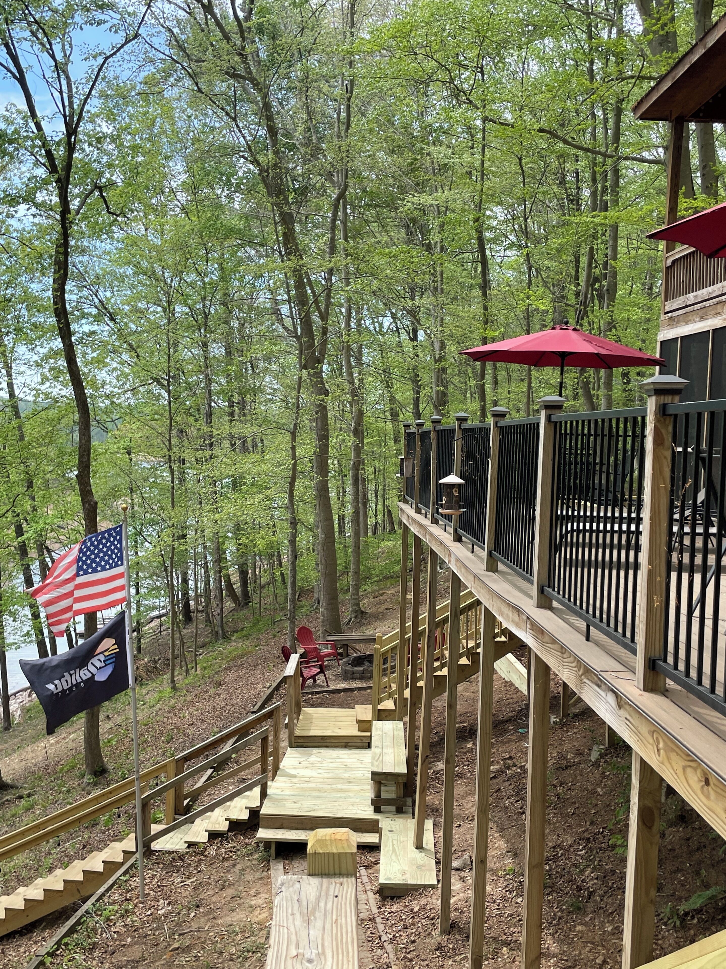 A wooden deck with a railing, a flag, and a red umbrella.