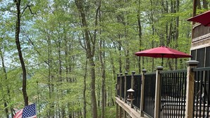 A wooden deck with a railing, a flag, and a red umbrella.
