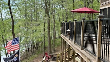 A wooden deck with a railing, a flag, and a red umbrella.