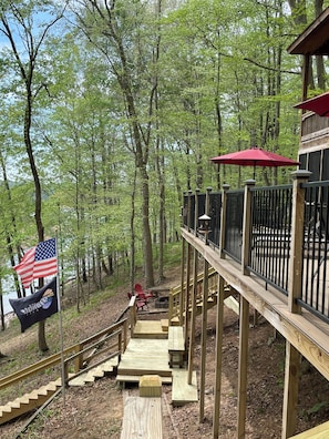 A wooden deck with a railing, a flag, and a red umbrella.