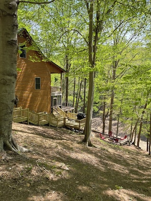 A wooden cabin with a deck and outdoor seating area surrounded by trees.