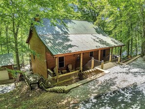 Eine Holzhütte mit Veranda, einer kleinen Treppe und einem Schotterweg.