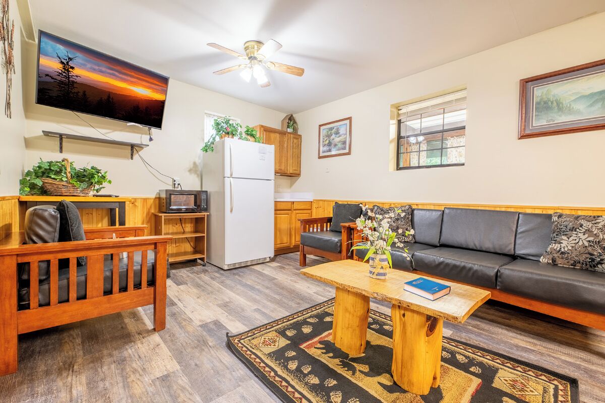 A cozy living room with a wooden bench, a sofa, a coffee table, and a TV mounted on the wall.