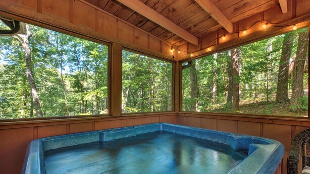 Un jacuzzi con vistas a un bosque a través de amplias ventanas.