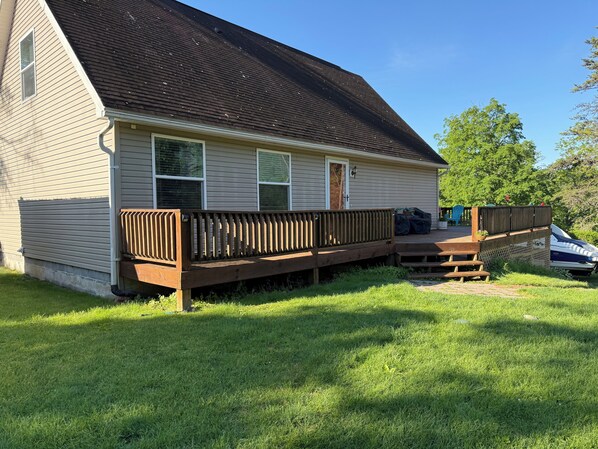 A single-story house with a wooden deck, a covered outdoor seating area, and a small front porch.