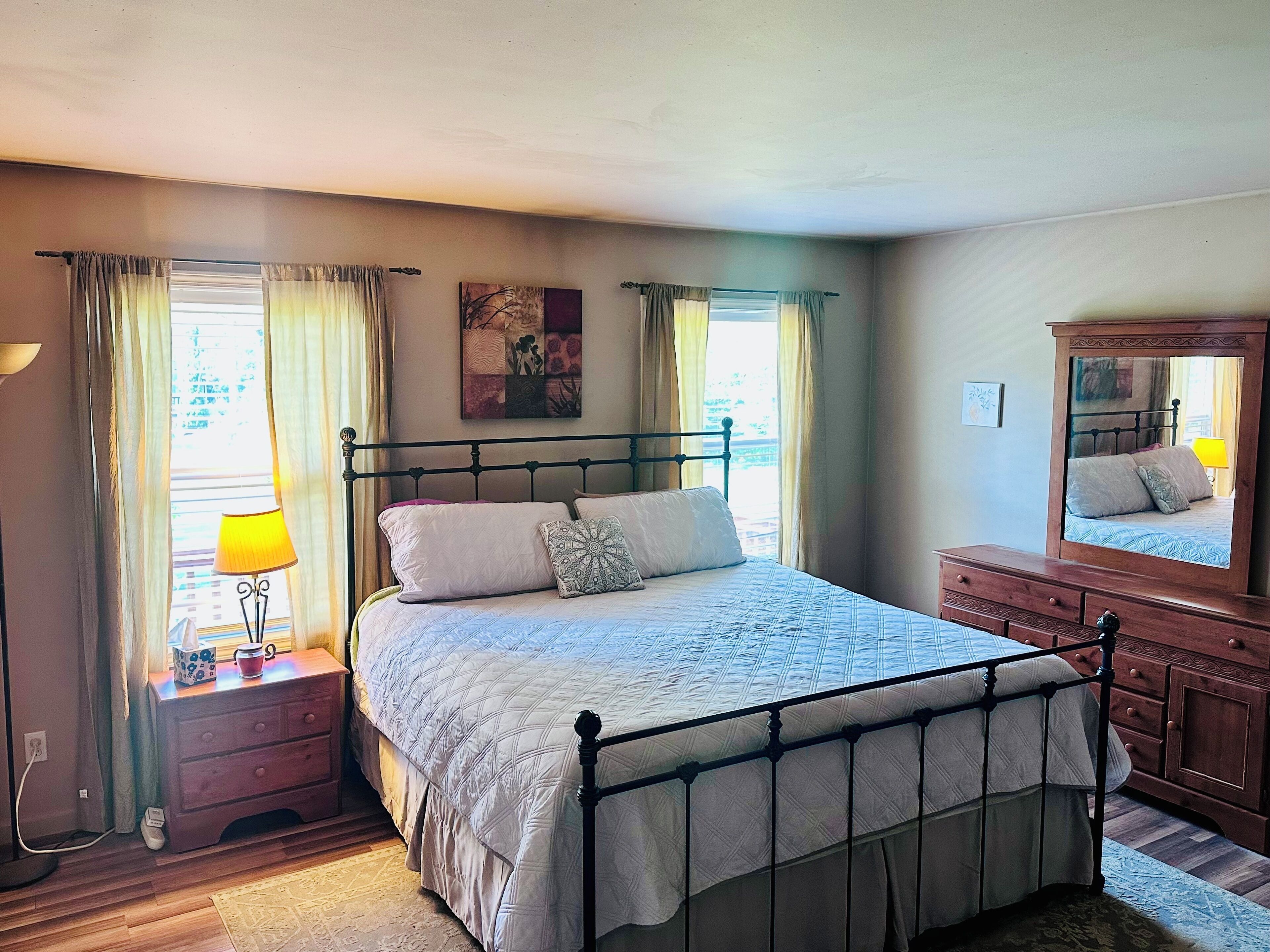 Une chambre à coucher avec un lit, une table de chevet, une lampe et une commode.