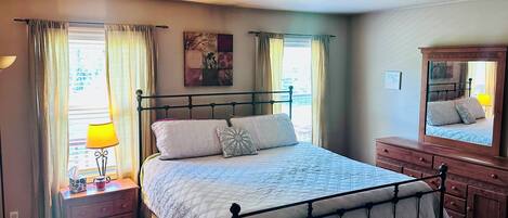 A bedroom with a bed, bedside table, lamp, and dresser.