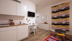 A modern kitchen with white cabinets, a built-in oven, and a flat-screen TV mounted above the counter.