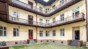 A multi-story building with balconies, a courtyard, and a bicycle parked outside. - RentPlanet - Apartament przy Plantach (Kraków)