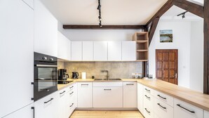 A modern kitchen with white cabinets, a wooden countertop, and a built-in oven. - RentPlanet - Apartament przy Plantach (Kraków)