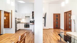A modern kitchen with white cabinets, a dining table, and a glass railing. - RentPlanet - Apartament przy Plantach (Kraków)