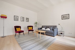 Uma sala de estar moderna com sofá, duas poltronas, uma mesa de centro, um abajur e quadros nas paredes.