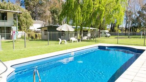 A rectangular swimming pool with a metal ladder on one side, surrounded by a tiled deck. - Kalganyi Holiday Park (Mount Gambier)