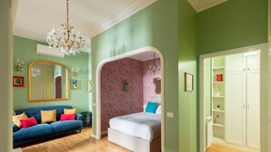 A bedroom with a bed, a blue sofa, a chandelier, and a wardrobe.