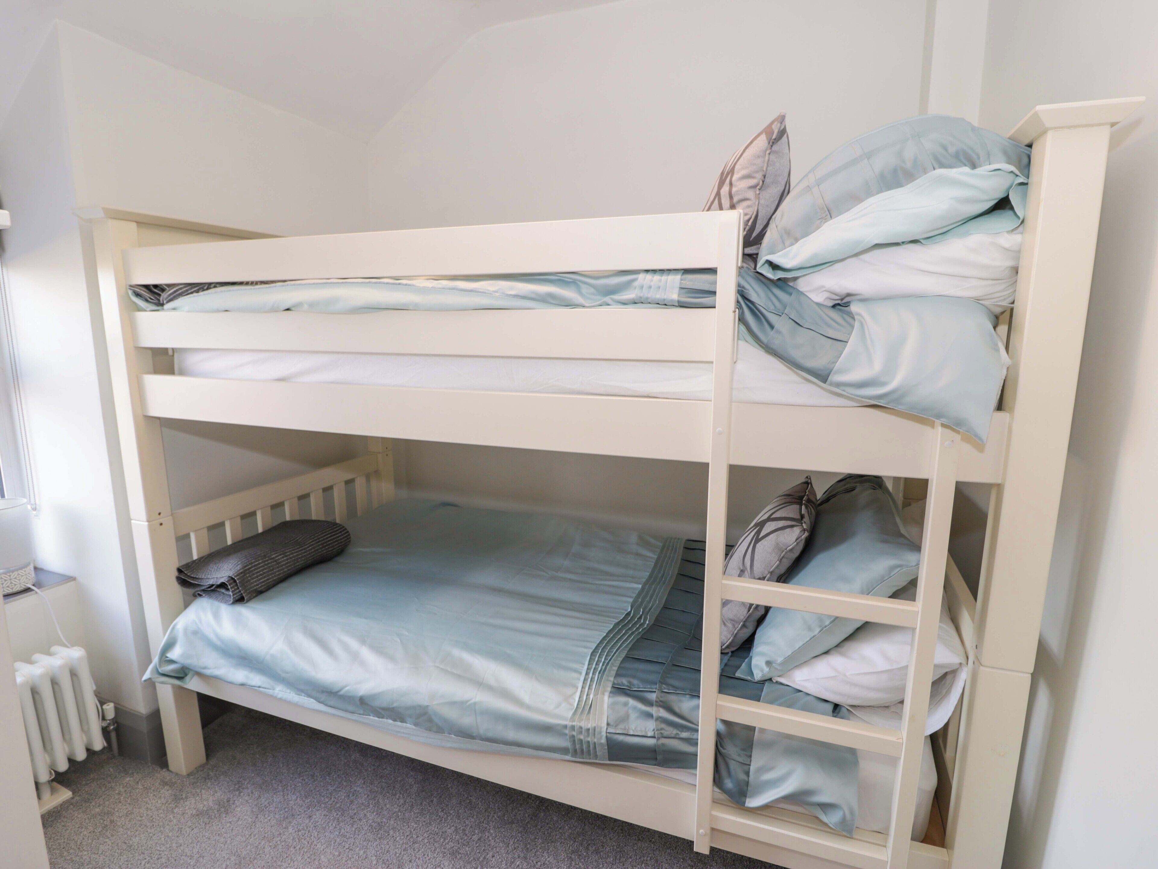A bunk bed with two levels, each with a mattress and pillows.
