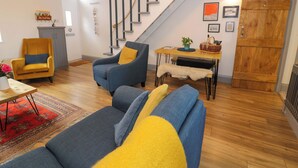 Ein modernes Wohnzimmer mit Treppe, Sofa, Sessel und Esstisch.