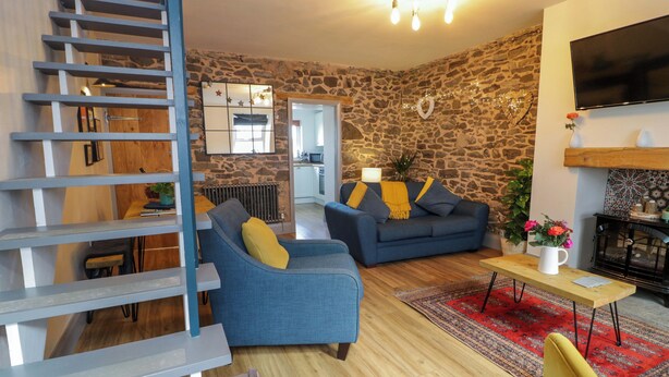 Ein modernes Wohnzimmer mit einer Steinwand, einem blauen Sofa, einem gelben Sessel, einem Holztisch und einem roten Teppich.