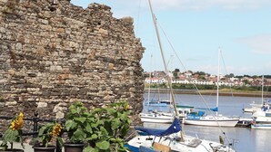 Eine Steinmauer, Kübelpflanzen und Boote in einem Hafen.