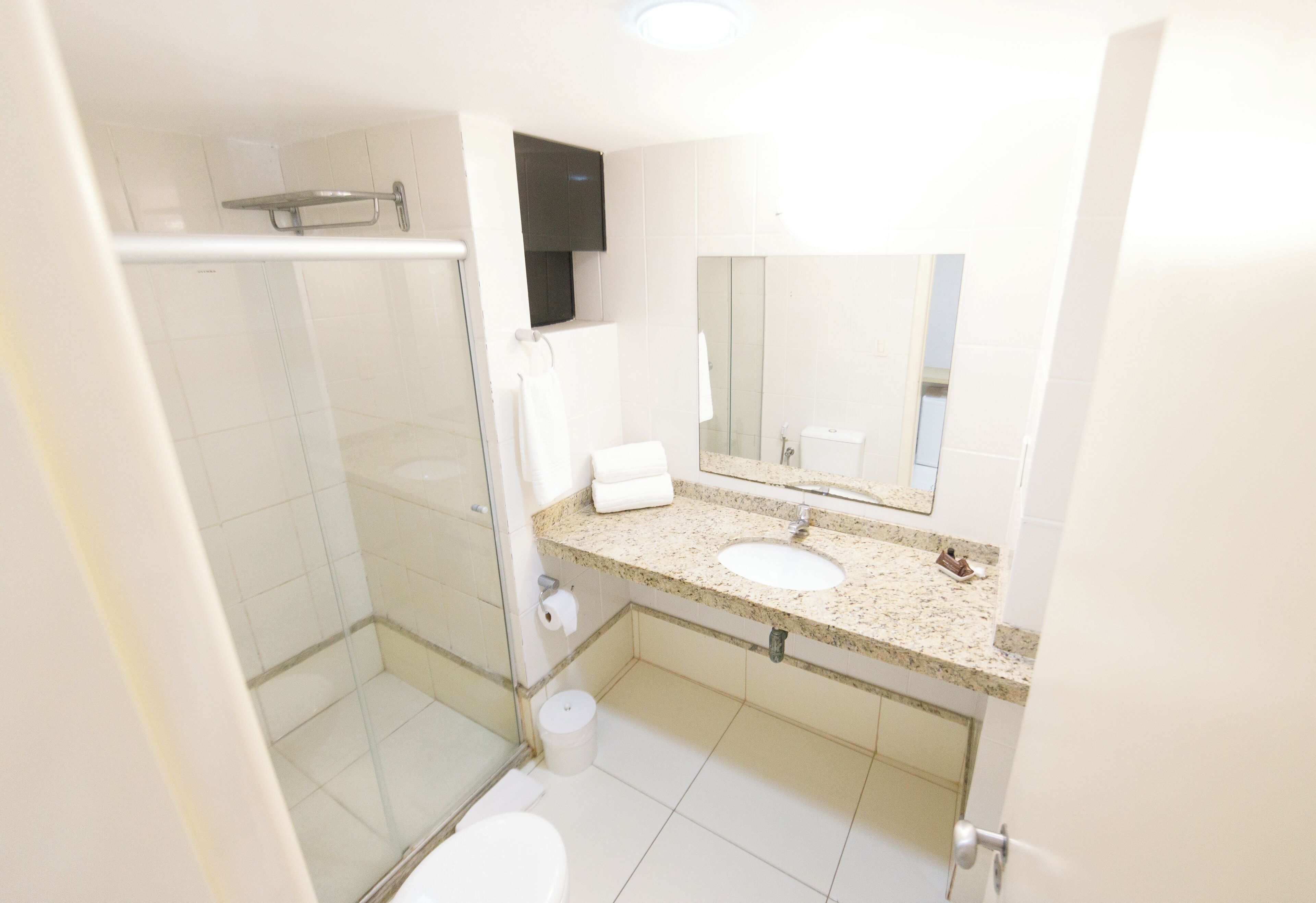 Un baño con cabina de ducha de vidrio, un lavabo con espejo y un inodoro.