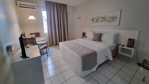 Una habitación de hotel con cama, mesitas de noche, escritorio y una silla.