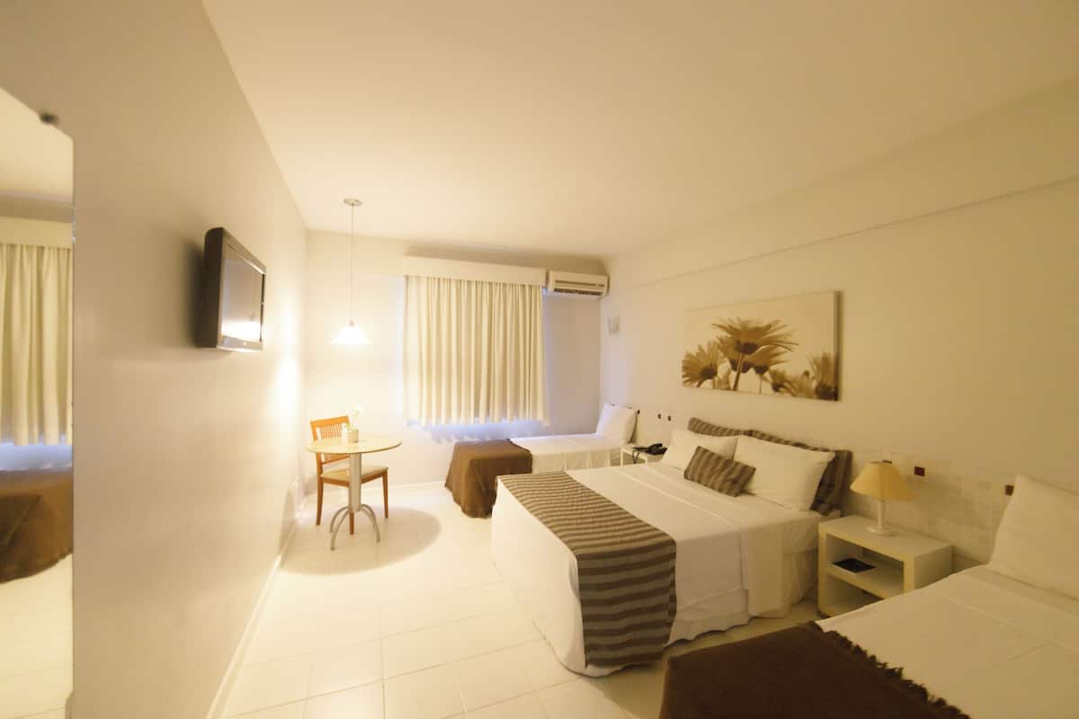 Une chambre d’hôtel avec un lit, un bureau, une chaise et un téléviseur fixé au mur.