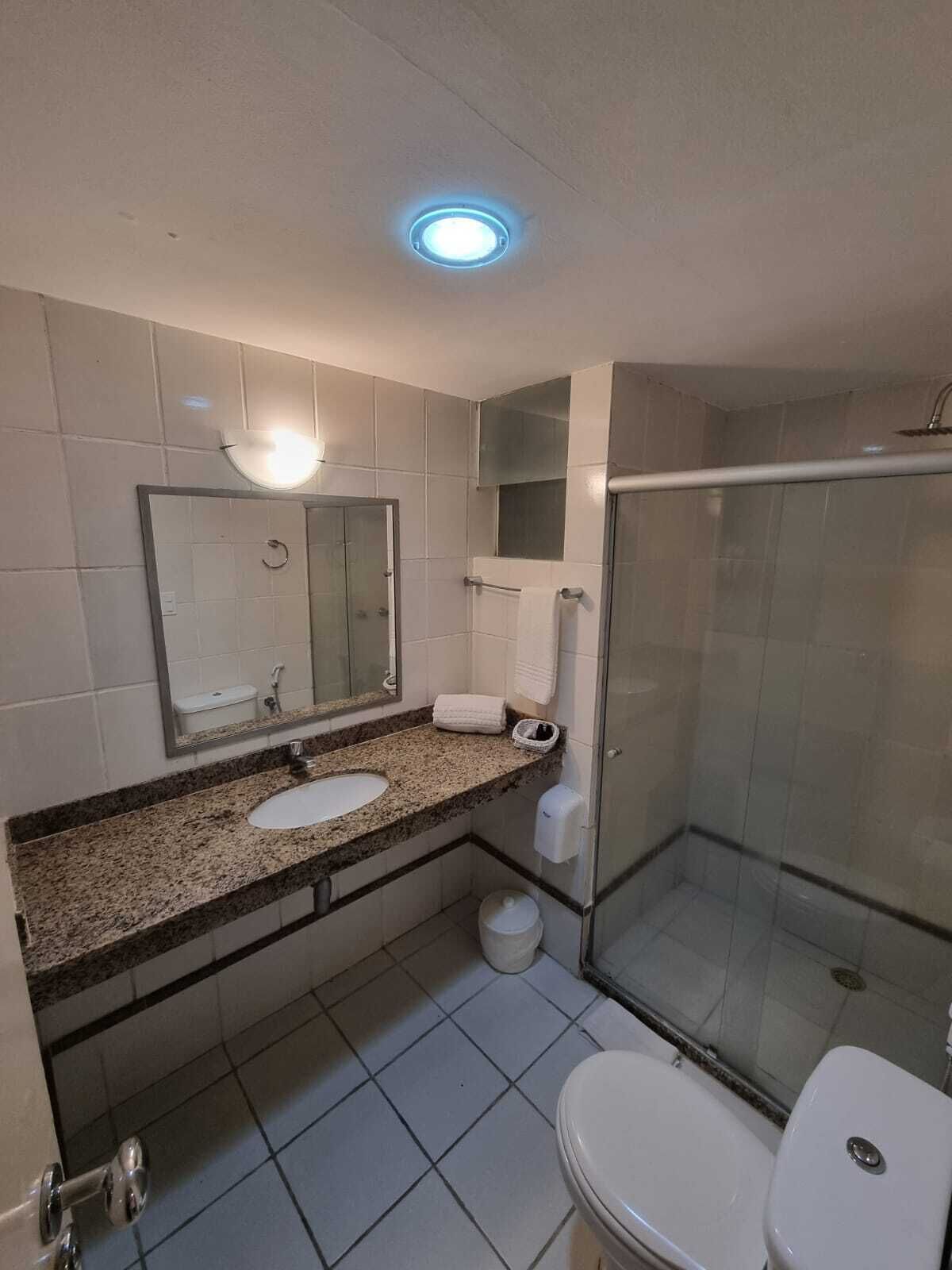 A bathroom with a sink, mirror, toilet, and glass-enclosed shower.