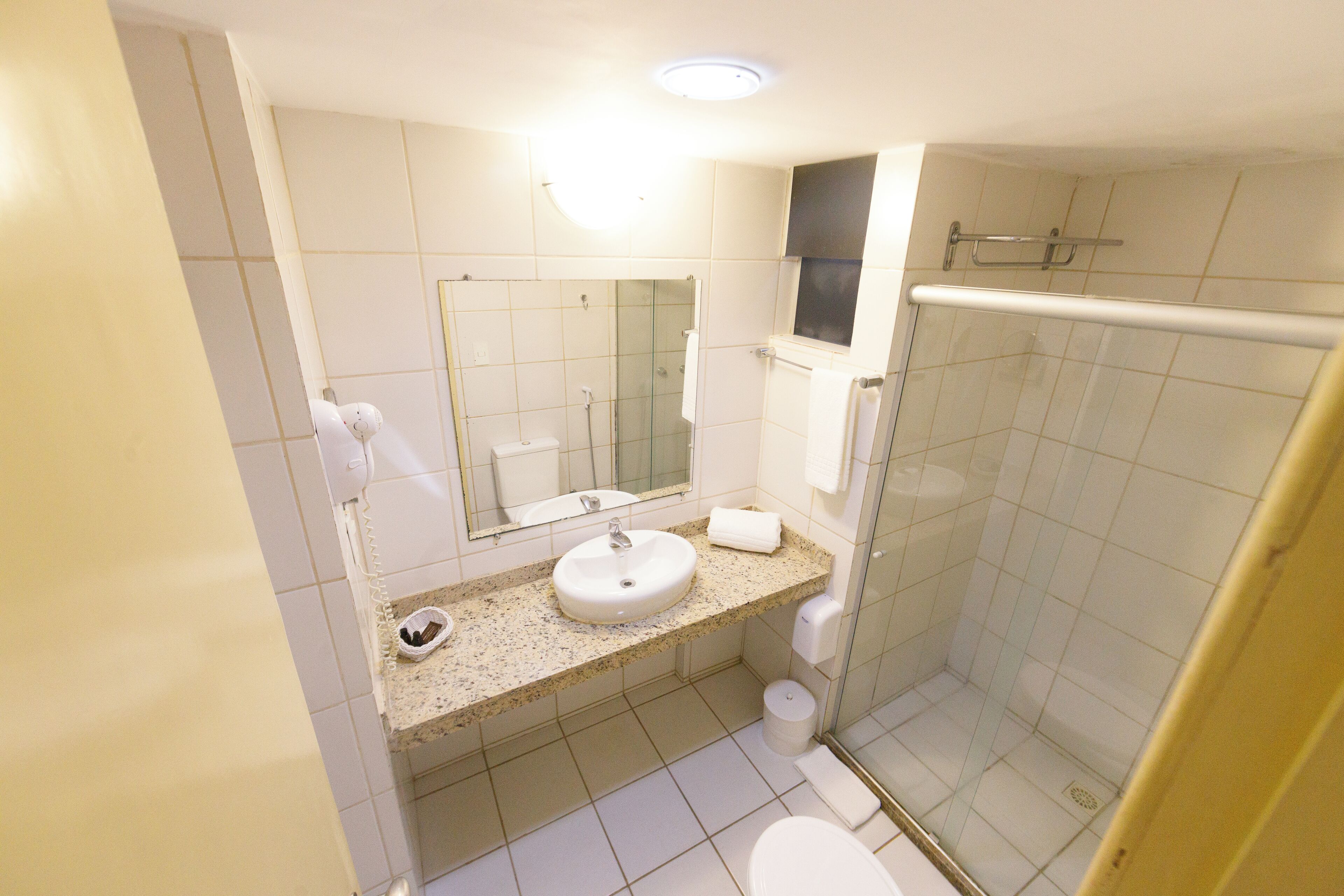 Een badkamer met een wastafel, spiegel, toilet en douchecabine.