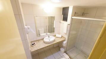 A bathroom with a sink, mirror, toilet, and glass-enclosed shower.