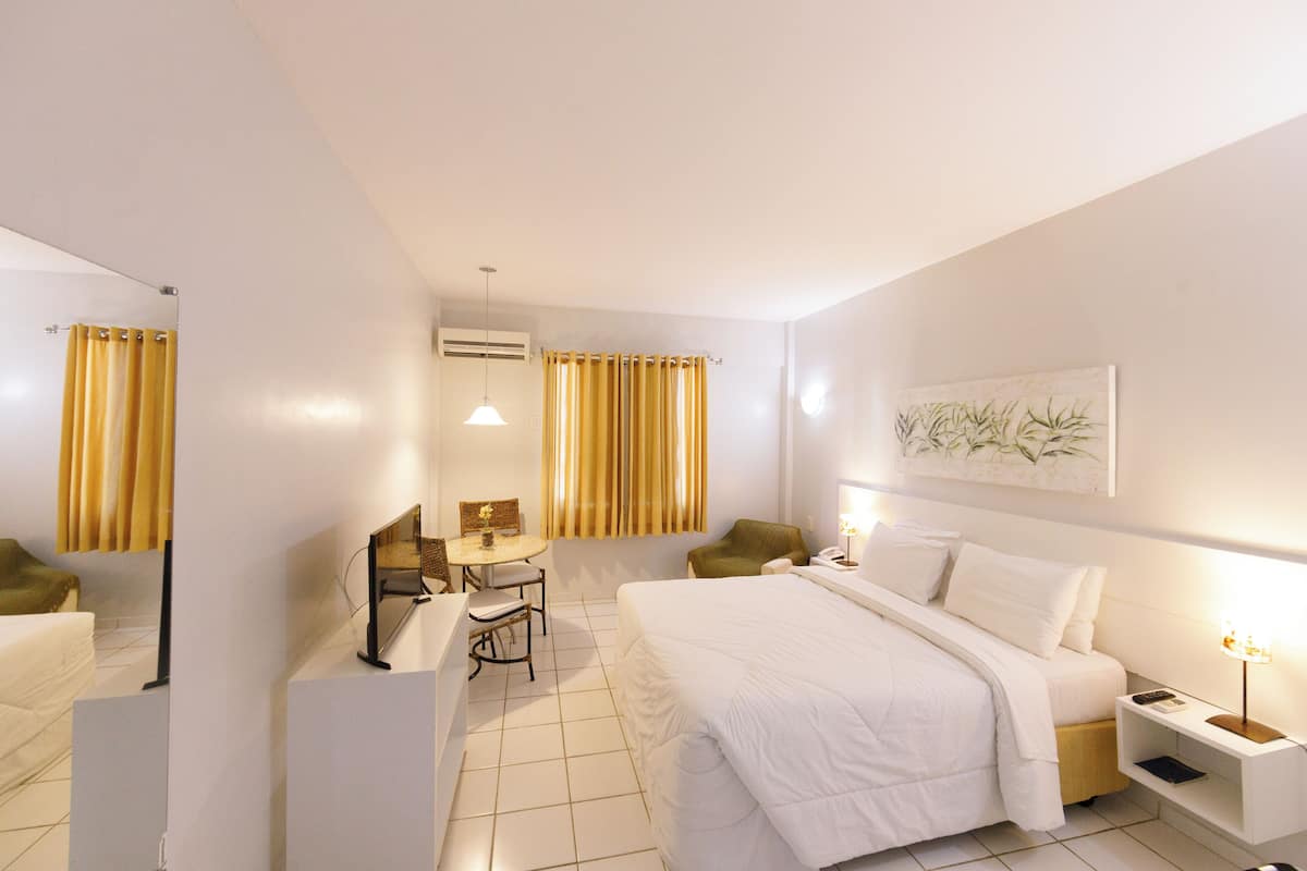 Une chambre d’hôtel comprenant un lit, une table de chevet, une lampe, une chaise, un bureau et un miroir.