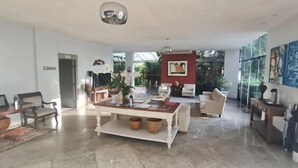 Amplia sala de estar con una mesa de centro, arreglos de asientos y ventanas grandes que ofrecen luz natural.