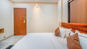 Un dormitorio con puerta de madera, cama con ropa de cama blanca y almohadas marrones, y cabecero con textura.